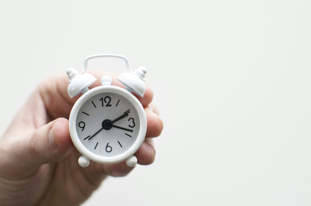 person holding white mini bell alarmclock