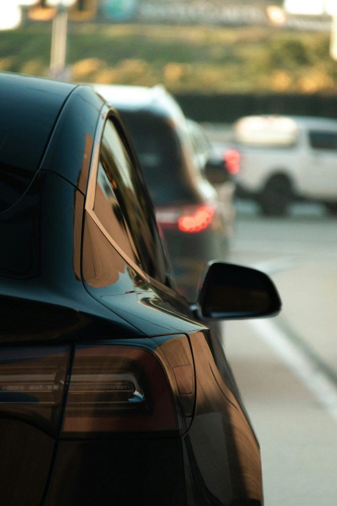 A black tesla car waits in traffic.